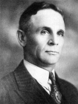 Black-and-white head-and-shoulders portrait of John Bracken in a dark suit and patterned tie.